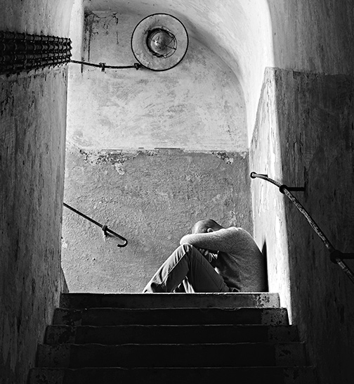 Foto en blanco y negro de un hombre deprimido sentado en unas escaleras