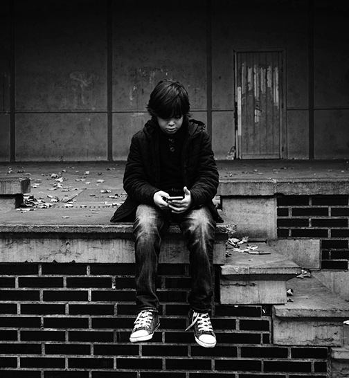 Foto en blanco y negro de adolescente sentado mirando un móvil